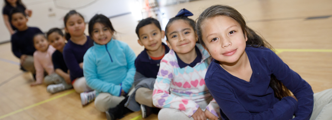 Students posing in a line sitting on the floor