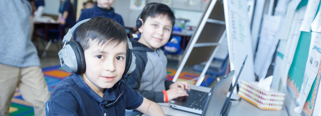 Student posing with headphones using a laptop